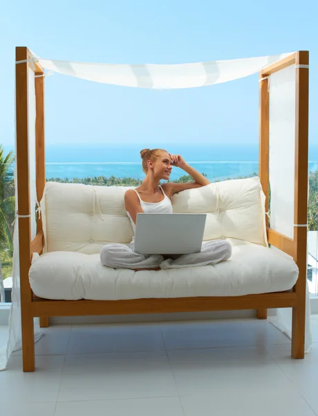 Kadınla gölgelikli koltuk üstünde laptop — Stok fotoğraf