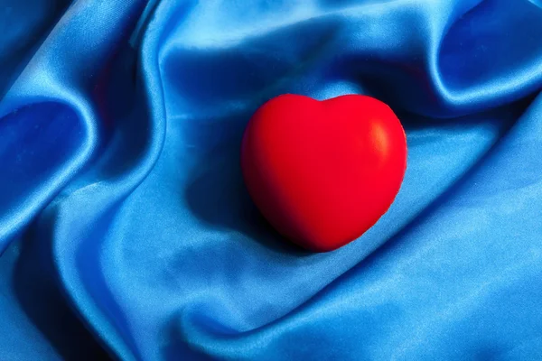 Червоне серце лежить на синьому шовковому текстилі з пробілом для копіювання — стокове фото