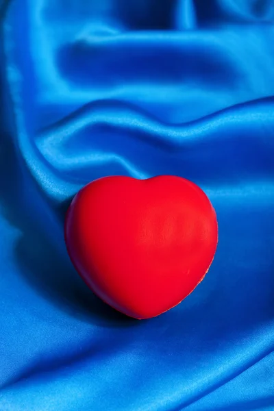 红色的心躺在蓝色的丝绸纺织与副本空间 — 图库照片