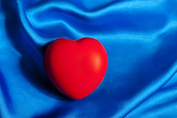 红色的心躺在蓝色的丝绸纺织与副本空间 — 图库照片