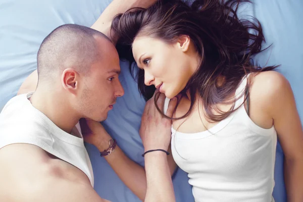 Jeune couple souriant se regardant tout en étant couché au lit — Photo