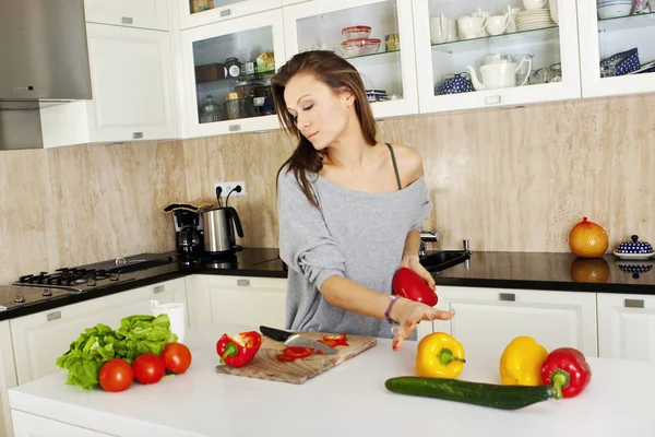 Portrett av en ung kvinne som tar salat på kjøkkenet sitt, mens hun er med – stockfoto