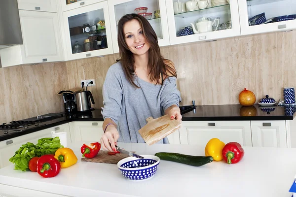 Portrett av en ung kvinne som tar salat på kjøkkenet sitt, mens hun er med – stockfoto
