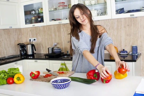 Portrait of a young woman doing a salad in her kitchen, while co — Stock Photo, Image