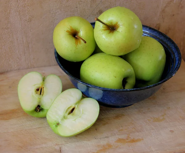 Яблука в синій мисці з нарізаним яблуком — стокове фото
