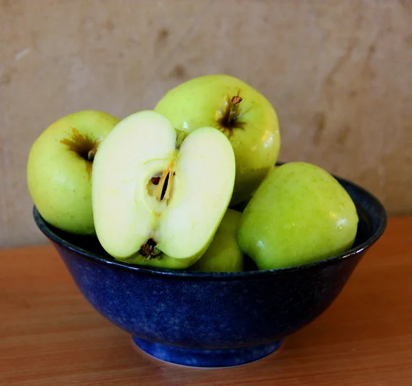 Blue bowl of apples with half a cut apple — Stock Photo, Image