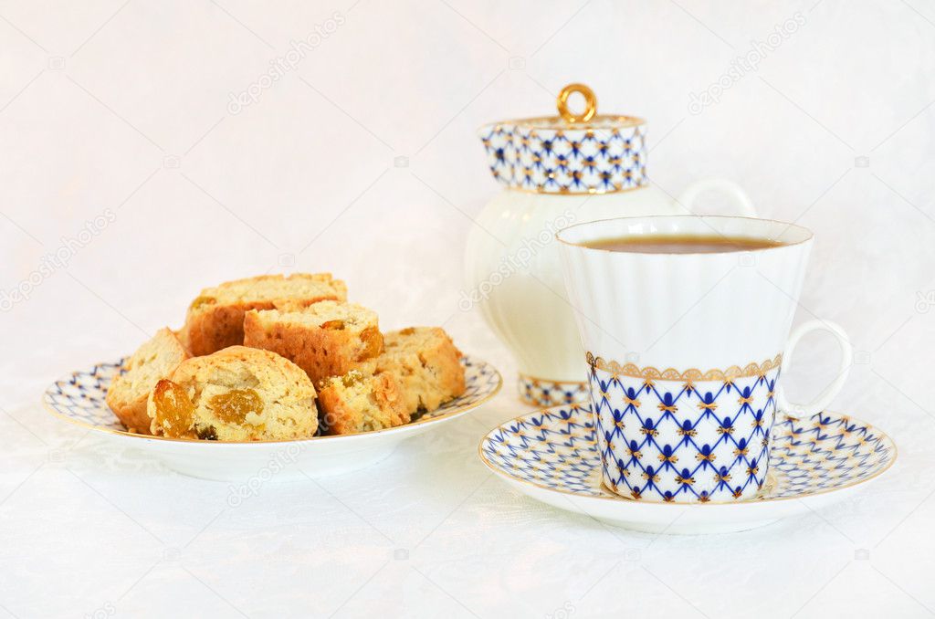 Tea party with cup of tea, plate with cakes and milk jug