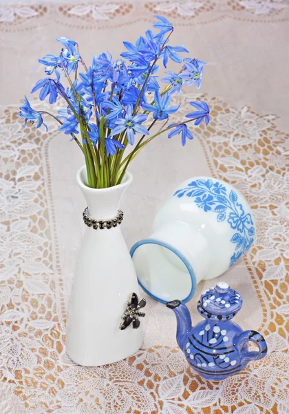 Bluebel, vaso e bule em uma toalha de mesa de renda, ainda vida — Fotografia de Stock