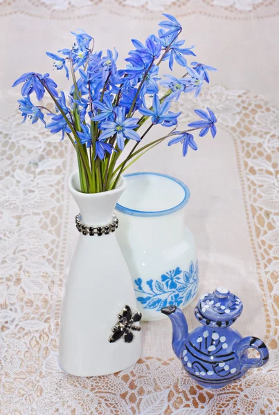 Bluebel, vaso e bule em uma toalha de mesa de renda, ainda vida — Fotografia de Stock