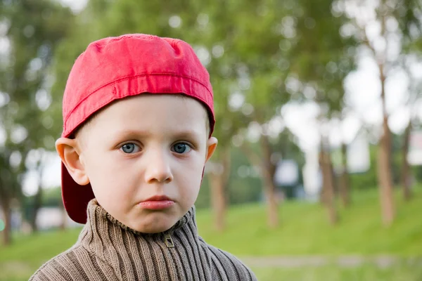 Triste petit garçon en casquette rouge à l'extérieur — Photo