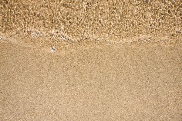Våg av vatten på sandstrand — Stockfoto