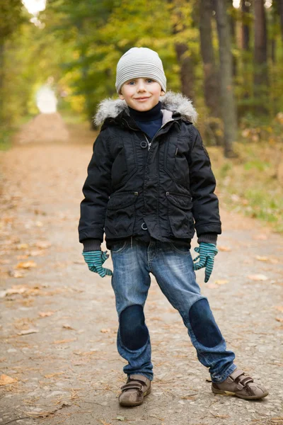Усміхнений хлопчик в осінньому лісі — стокове фото