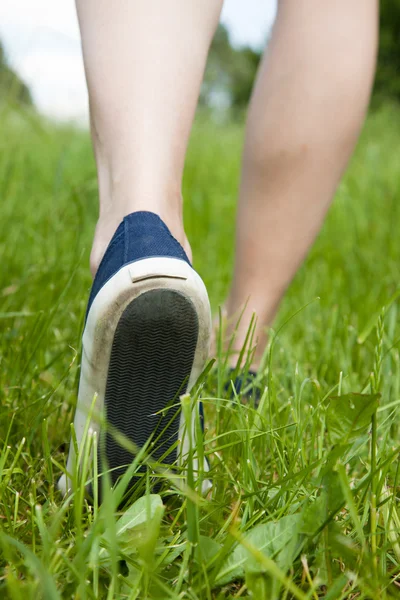 Caminhando na grama verde em sapatos esportivos — Fotografia de Stock