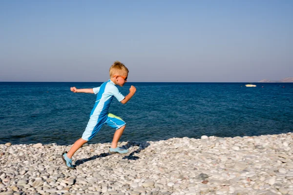 Chlapec běží na oblázkové pláži — Stock fotografie