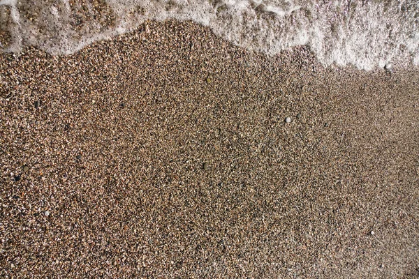 Wave of water on gravel beach — Stockfoto