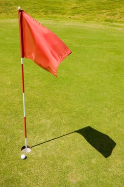 bir golf sahası üstünde kırmızı bayrak