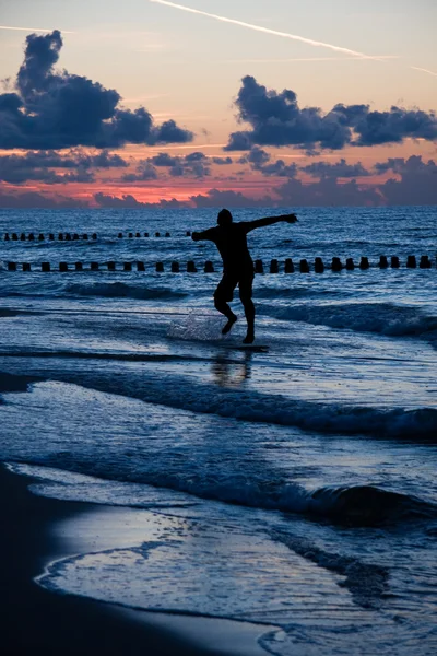 ビーチ海岸に夕日の光の中で散歩をして人間のシルエット — ストック写真