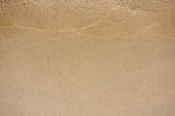 Våg av vatten på sandstrand — Stockfoto