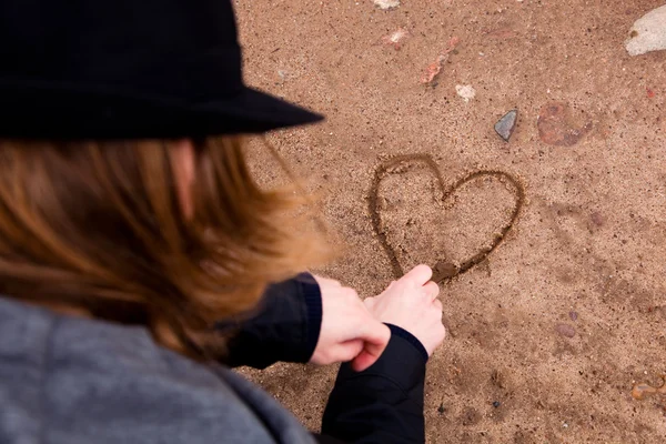Jonge man tekening hart op grond — Stockfoto