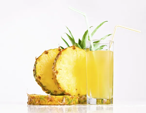 Свіжий ананасовий сік з нарізаним ананасом на білому тлі — стокове фото