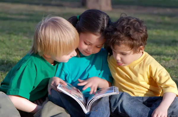 Grupp barn med boken på en gräs i parken — Stockfoto