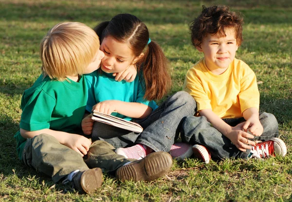 Groupe d'enfants avec le livre sur l'herbe dans le parc — Photo