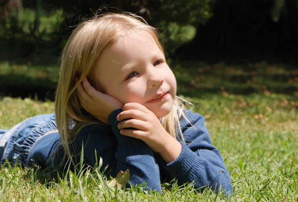 Маленька дівчинка лежить на траві в парку — стокове фото