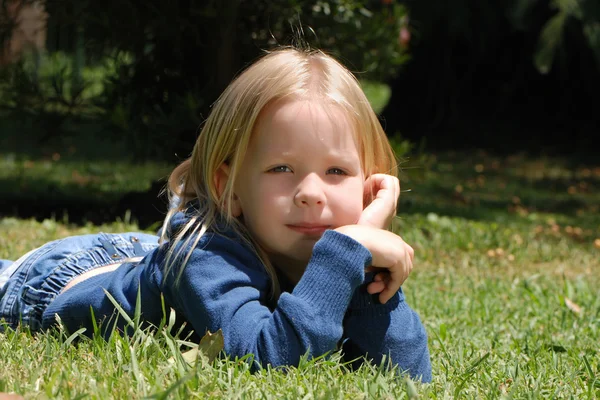 Dziewczynka leżąca na trawie w parku — Zdjęcie stockowe