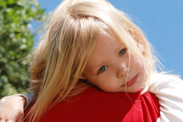 Маленькая девочка на плече у матери на фоне неба — стоковое фото