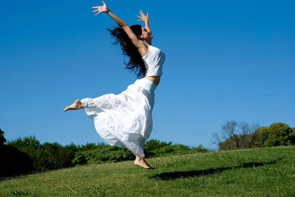 Mutlu kız beyaz bir elbise içinde atlama — Stok fotoğraf