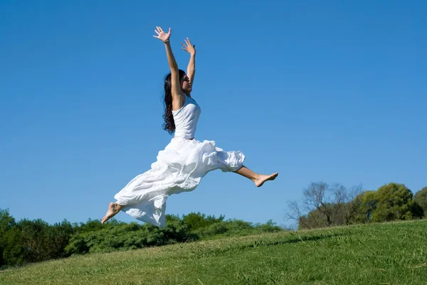 Щаслива дівчина стрибає в білій сукні — стокове фото