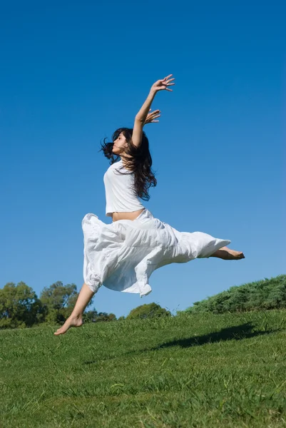 Šťastná dívka, která skočila v bílých šatech — Stock fotografie