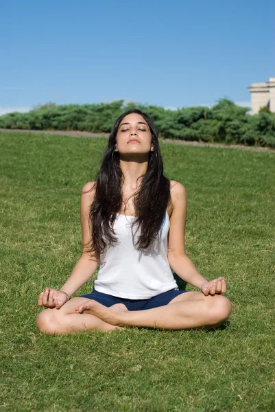 Красивая девушка медитирует в зеленой траве — стоковое фото