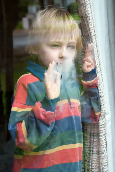 Το μικρό αγόρι πίσω από ένα υγρό παράθυρο — Φωτογραφία Αρχείου