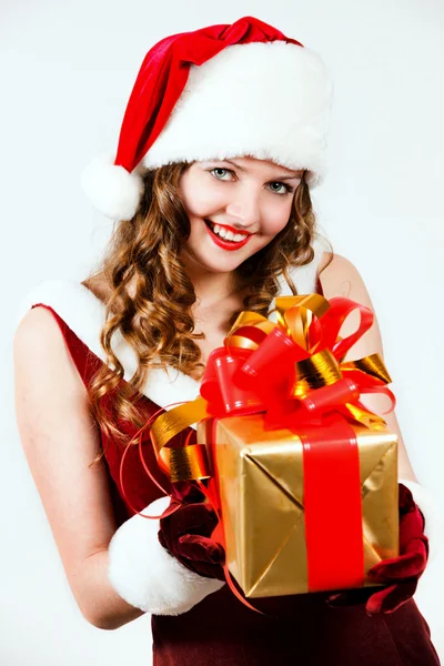 Bella donna in abito rosso e cappello di Babbo Natale con un grande regalo — Foto Stock