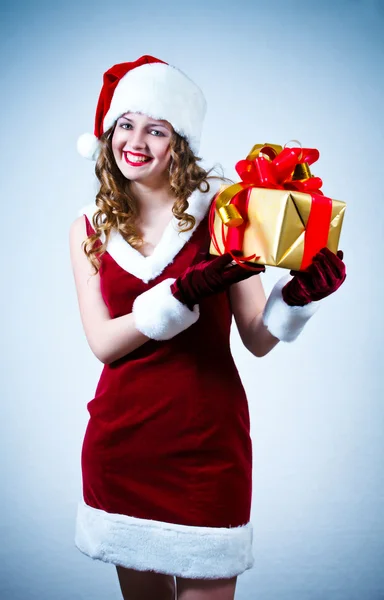 Bir kırmızı elbise ve santa şapka büyük bir hediye ile güzel bir kadın — Stok fotoğraf