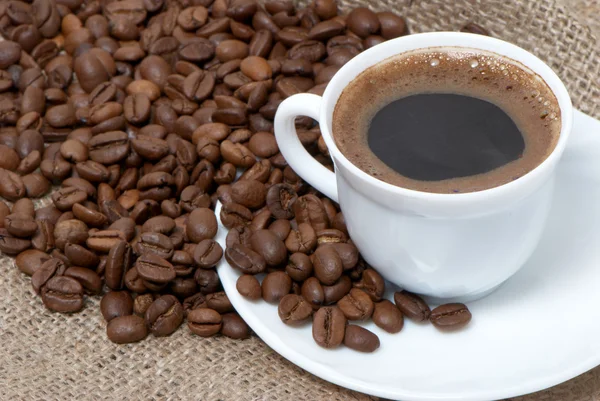 Copo de café close-up sobre grãos de café torrados escuros — Fotografia de Stock