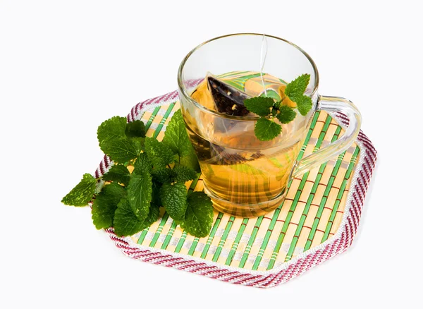 Beyaz bir arka plan üzerinde çay bardağı ile nane yaprakları — Stok fotoğraf