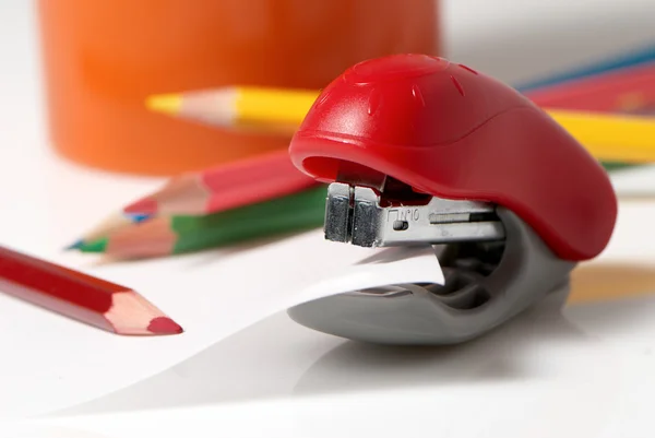Красный степлер и цветные карандаши на белом фоне — стоковое фото
