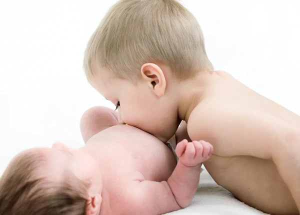 Маленький мальчик целует ее новорожденную сестру — стоковое фото