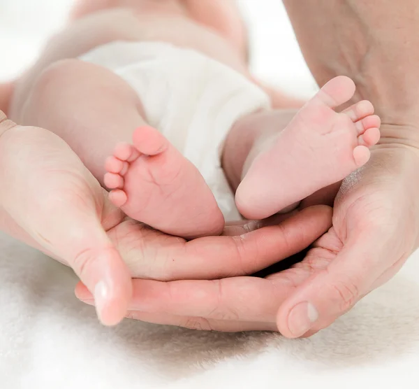 Nahaufnahme der Hand eines Vaters und der Füße eines Babys — Stockfoto