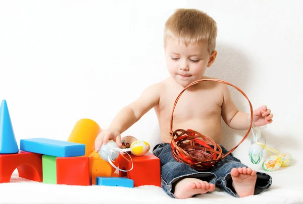 Ребенок, окруженный игрушками на белом фоне — стоковое фото