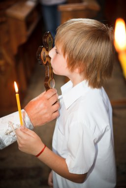 The little boy a kissing cross in church clipart