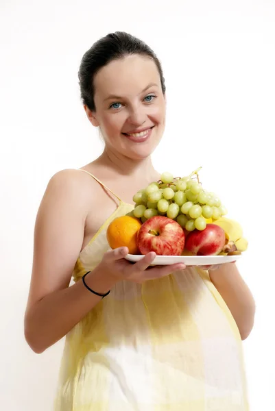 Η έγκυος γυναίκα με φρούτα σε ανοιχτόχρωμη επιφάνεια — Φωτογραφία Αρχείου