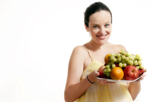 Η έγκυος γυναίκα με φρούτα σε ανοιχτόχρωμη επιφάνεια — Φωτογραφία Αρχείου