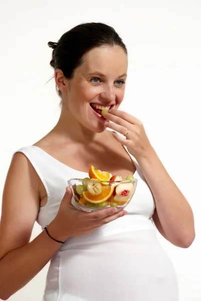 Беременная женщина с фруктами на светлом фоне — стоковое фото