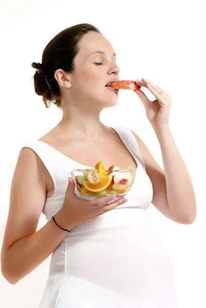 La mujer embarazada con fruta sobre un fondo claro — Foto de Stock