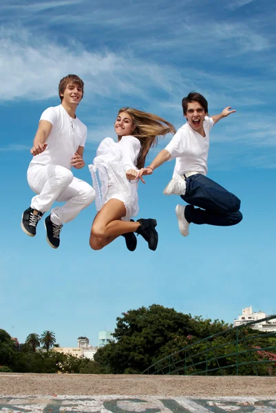 Skupina přátel v skok proti město a obloha — Stock fotografie