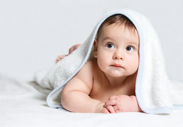 Маленький ребенок под белым полотенцем — стоковое фото