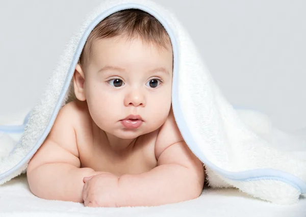 Kleine baby onder witte handdoek — Stockfoto